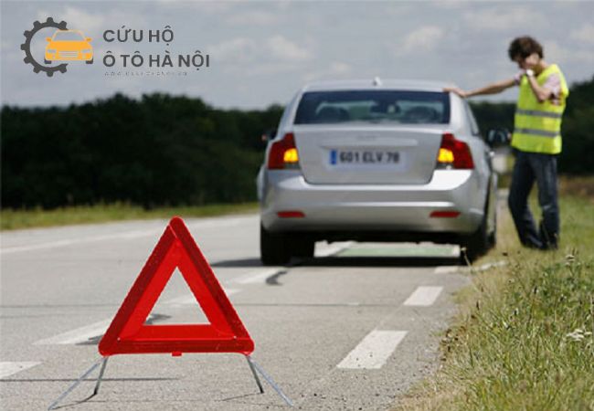 Người lái xe mặc áo phản quang, đặt biển tam giác cảnh báo khi xe chết máy giữa đường cao tốc. Người lái xe mặc áo phản quang, đặt biển tam giác cảnh báo khi xe chết máy giữa đường cao tốc.
